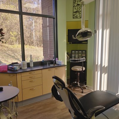 operatory with chair, dental equipment, a counter and large windows