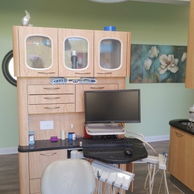 operatory with chair, computer monitor, shelving and artwork on the wall